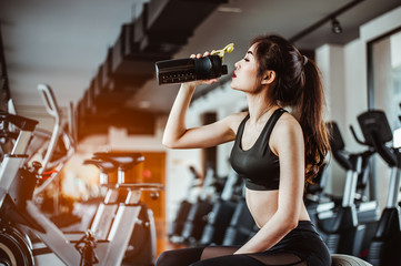 Plakat young fitness woman tired in gym drink protein shake.exercising concept.fitness and healthy lifestyle
