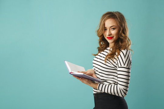 Pretty smiley blonde girl student with book over blue background