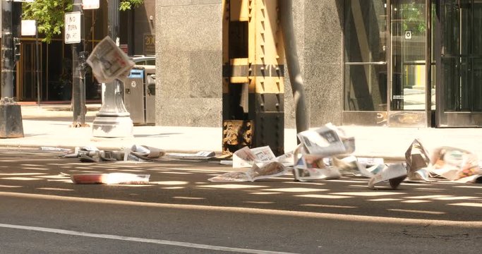 Newspaper litter through the city streets blowing in the wind as a car passes by