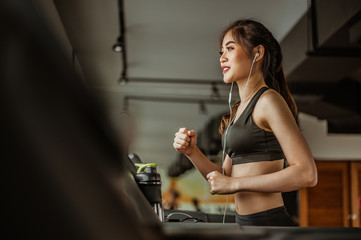 Portrait of Fitness woman running on treadmill in gym listening to music.exercising concept.fitness and healthy lifestyle.