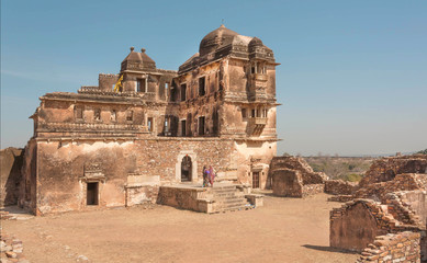 Old destroyed palace with brick towers and some indian women in sari, India.