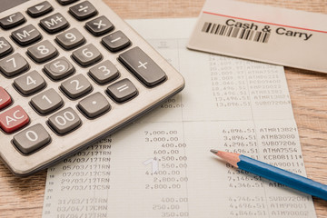 Calculator, cash card, pencil, bankbook Put on a wooden table.