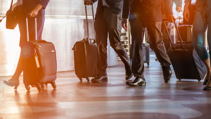 Close up of businessman team carrying suitcase while walking through a passenger boarding bridge.people and traveling luggage walking in airport terminal building.