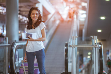 Young woman pulling suitcase in modern airport terminal. Travelling guy with his luggage while waiting for transport. Rear view. Copy space