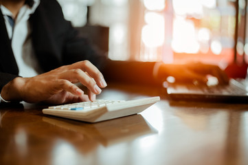 plan and strategy in business.risk concept.hand of man has piling up and stacking a wooden block.Businessman Building The Success.using calculator to calculate.