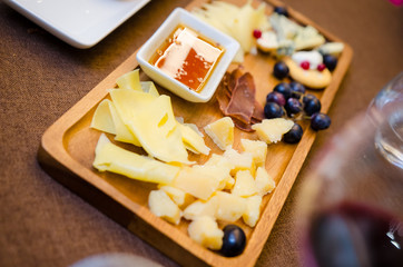 Cheese plates served with grapes, jam and nuts on a wooden background, Top view