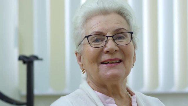 Portrait of happy senior woman in new eyeglasses smiling at camera in ophthalmology clinic