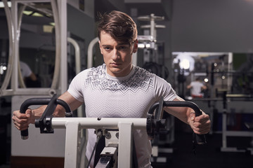 one young man 20 years old, fitness equipment exercise, indoors gym. upper body, medium shot. arm pull push