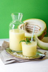 smoothies melon on a green background, glass bottle and slice next to, summer drink, cocktail