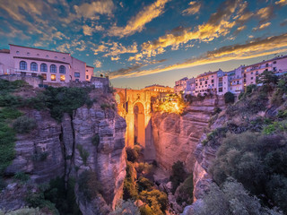 Puente Nuevo bridge and the houses built on the edge of the cliff at dusk, in the ancient city of Ronda, Spain.