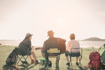 group of young people enjoy in music of drums and guitar on camping trip.