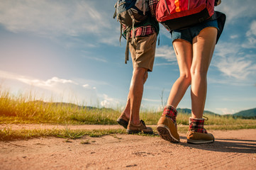 Hikers with backpacks walking trough forest path wearing mountain boots with focus on the shoes.