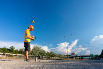 Worker or builder (Surveyor) with GPS on construction site during the sunny day with blue sky in background
