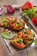 Rye bruschetta with beans, sweet peppers, arugula and red onion, vertical 