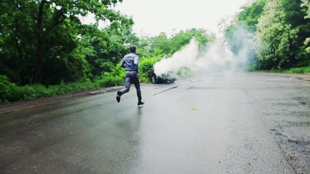 A mature man running towards the car in fire after an accident.