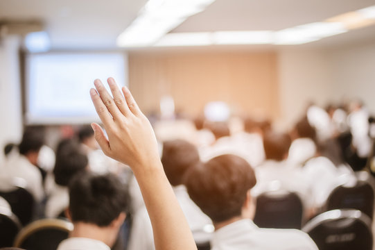  businessman raising hand during seminar. Businessman Raising Hand Up at a Conference to answer a question.