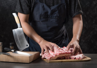 Chef cook cuts large piece of pork meat on wooden cutting board with knife,concept of cooking