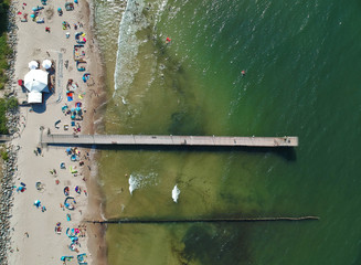 Aerial view on wooden pier on sea with sand beach and breakwaters