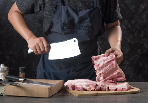 Chef cook cuts large piece of pork meat on wooden cutting board with knife,concept of cooking