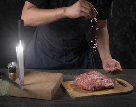 Chef cook pours salt on pork or beef meat,concept of cooking