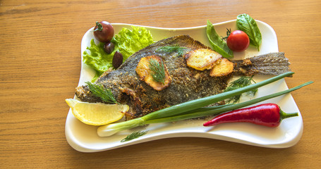 Fried flounder or flatfish served with vegetables and greens