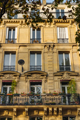 Fototapeta na wymiar Old Paris residential buildings with balconies and flowers. Beautiful facade of typical french city house. Background. European architecture and city life, lifestyle and expensive real estate concept