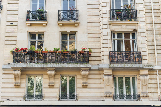 Old Paris residential buildings with balconies and flowers. Beautiful facade of typical french city house. Background. European architecture and city life, lifestyle and expensive real estate concept