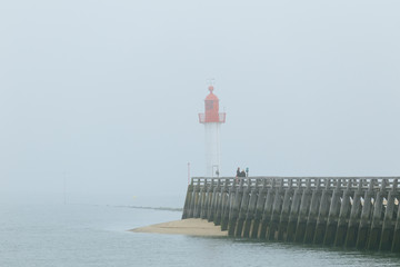 Fototapeta na wymiar Pier and lighthouse in the harbour of Deauville on a misty morning in Normandy, France. English channel seascape