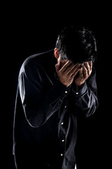 Man suffering from headache against black background,Dramatic portrait of a sad