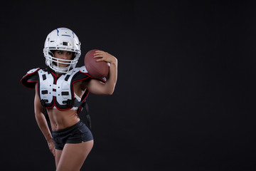Portrait of sexy attractive young girl in a sports outfit for rugby with the helmet strongly looking forward standing on black background