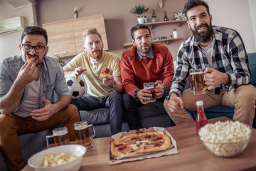 Young men drink beer,eat pizza and cheering for football