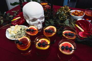 Halloween party catering with snacks, cocktails and white skull decoration on red table