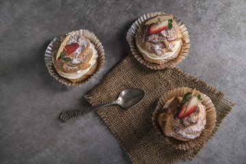 Homemade profiteroles with cream, strawberries and mint. Dessert for gourmets.
