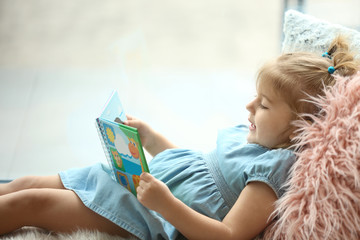 Cute little girl with book at home