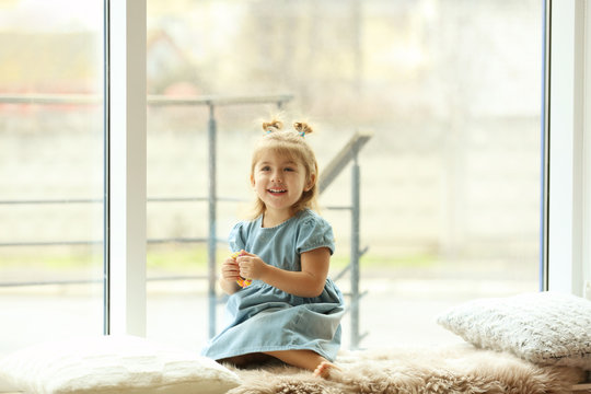 Cute little girl near window at home