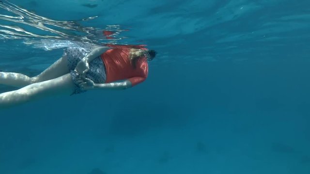 Tourist swim under surface of the blue water and look at a pod of Spinner Dolphins (Underwater shot, 4K / 60fps)
