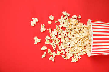 Paper cup with tasty fresh popcorn on color background, top view