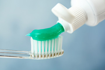 Fototapeta na wymiar Squeezing toothpaste on brush against color background, closeup