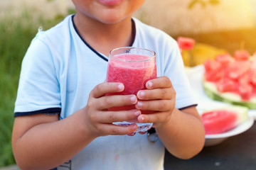Young boy holding Healthy glass of watermelon smoothie