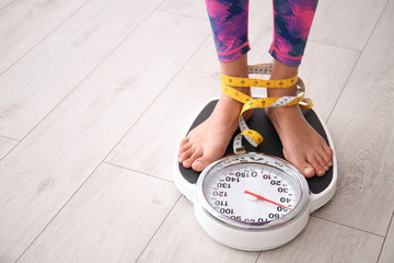 Woman tied with tape measuring her weight using scales on floor