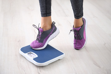 Woman measuring her weight using scales on floor