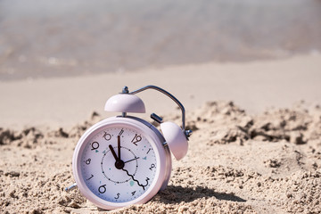 Vacation time. Alarm clock on the sand.