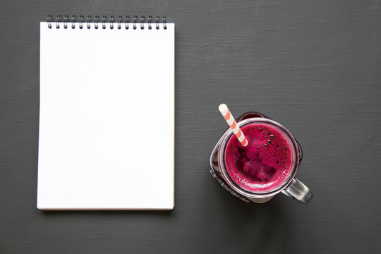 Beetroot Smoothie In Glass Jar Mug With Blank Notepad Over Black Background, View From Above. Flat Lay, Overhead. Closeup.