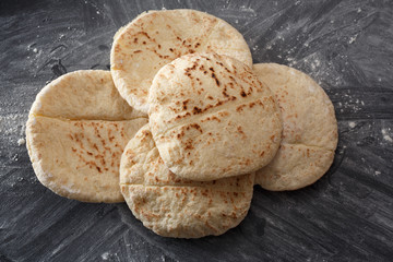 Pita bread on a black table sprinkled with flour