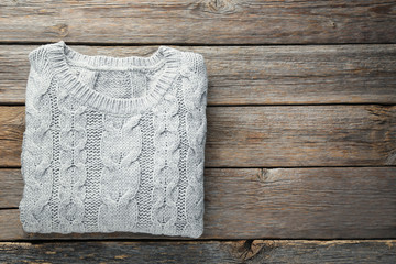 Knitted grey sweater on wooden table