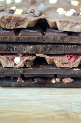 A gift pack of artisan handmade chocolate. Chocolate bars with dried fruit on dark background, front close up view.

