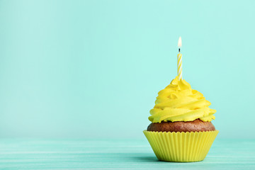 Tasty cupcake with candle on mint background