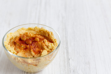 Bowl of Hummus with spices on a white wooden surface, side view. Close-up.