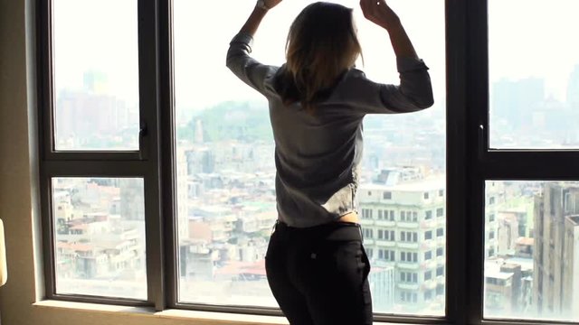Happy woman dancing by window at home
