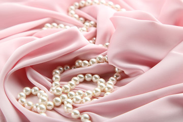 Pearl necklace on pink satin fabric